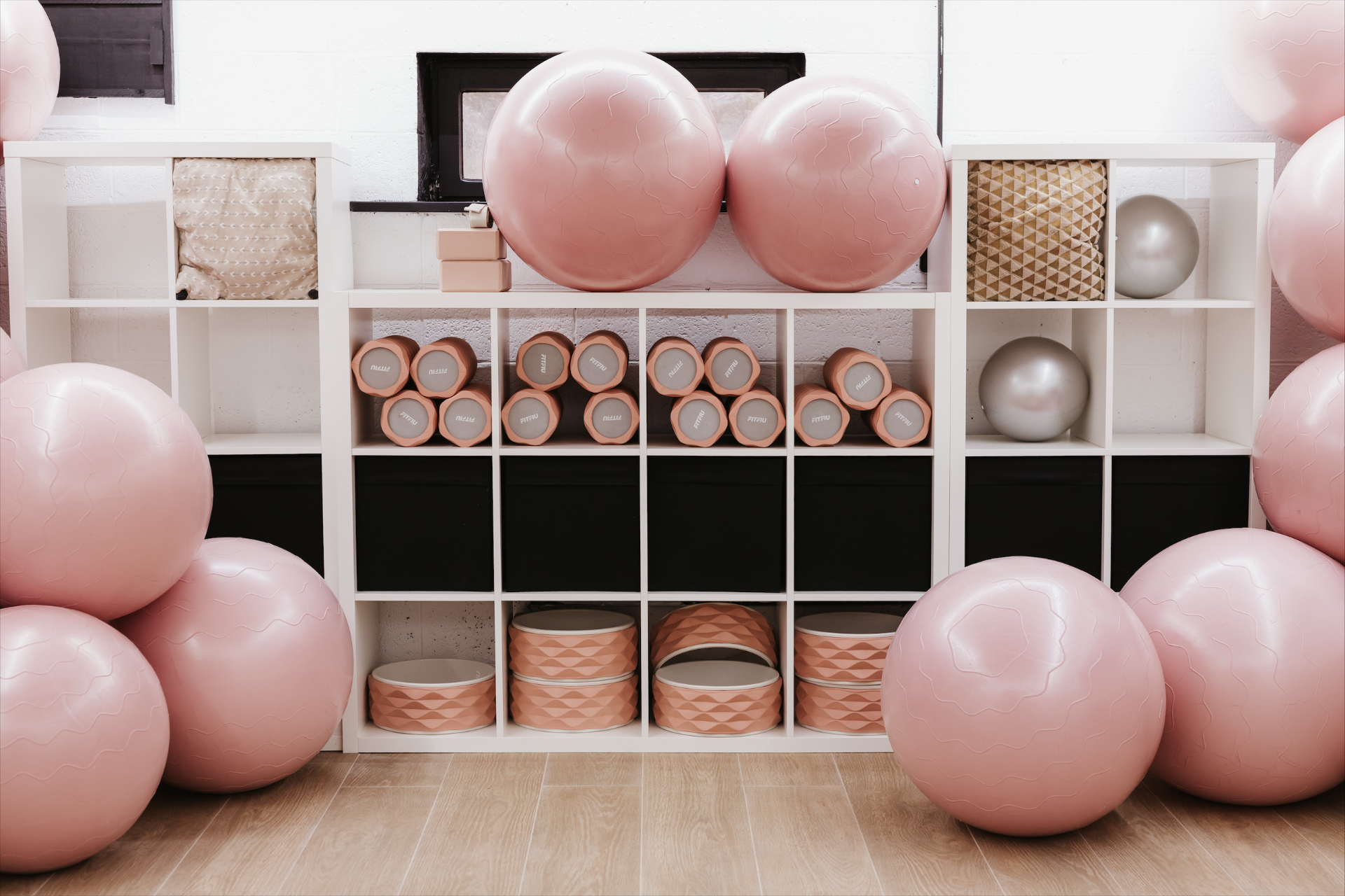 Étagère avec ballons de Pilates roses et rouleaux de mousse